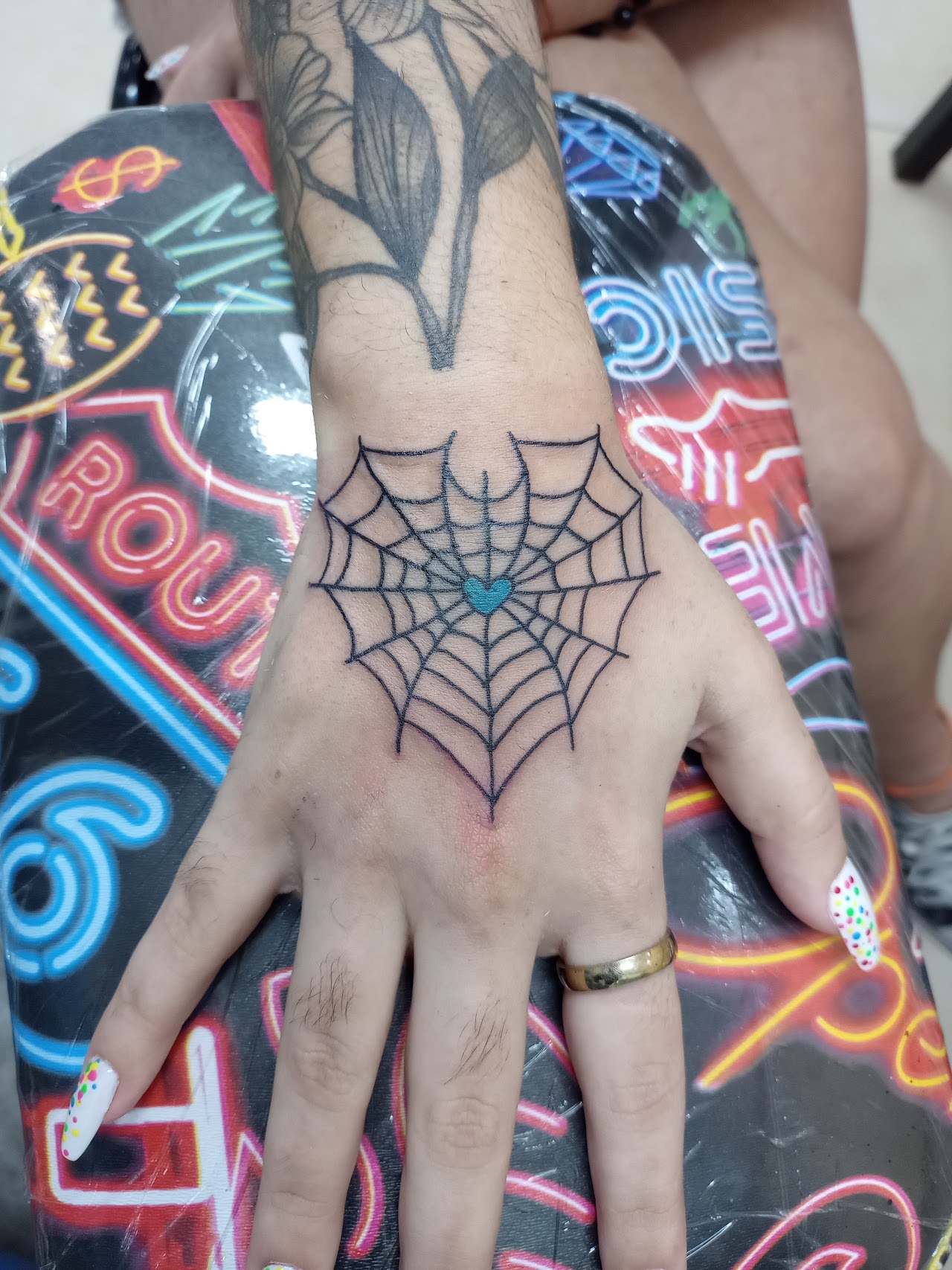 Tatuaje de telaraña con corazón en el dorso de la mano